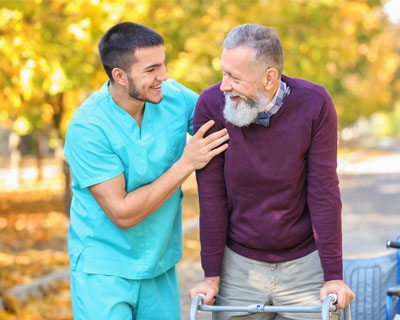 a caregiver accompanying a senior man walk outside